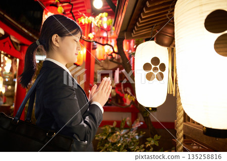 一位身著西裝的女子夜間在神龕前祈禱的側影 135258816