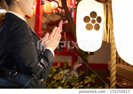 夜裡，一位穿著套裝的女子在神龕前祈禱，她的雙手清晰可見。 135258817