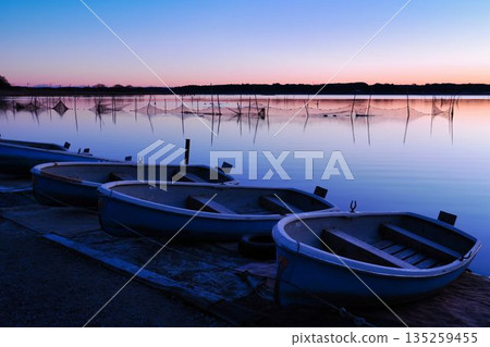 Scenery of a morning glow and a small boat reflected on the calm waters of Lake Inbanuma 135259455