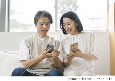 A smiling couple in their 50s looking at a smartphone screen 135260417