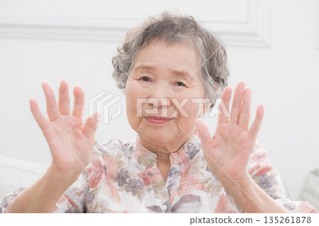 一位微笑的老婦人揮舞著雙手告別。畫面健康，令人心情舒暢。 135261878