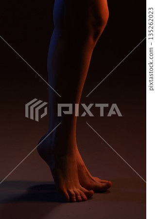 Legs and feet posed upright, lit with warm and cool light in a studio setting Legs and feet posed upright, lit with warm and cool light in a studio setting 135262023