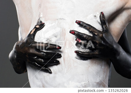 Body painting activity with one person applying paint on another person in a studio setting 135262026