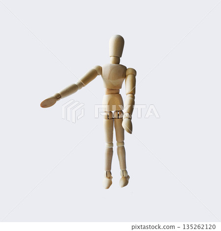 A wooden mannequin stands upright with one arm extended. The figure is jointed and has a natural wood finish, suitable for artistic reference or display 135262120