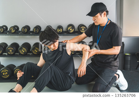 A man training with shoulder pain and a male sports physiotherapist A man training with shoulder pain and a male sports physiotherapist 135263706