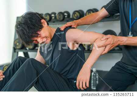 一名肩部疼痛的男子正在訓練，以及一名男性運動物理治療師 135263711