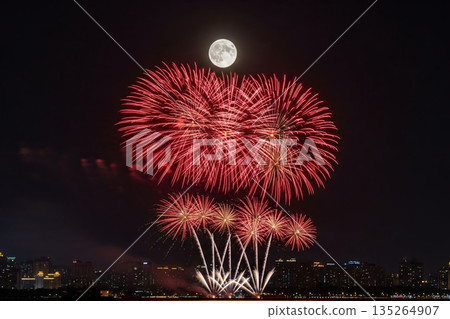 Festive Fireworks Display Over City Under Full Moon Festive Fireworks Display Over City Under Full Moon 135264907