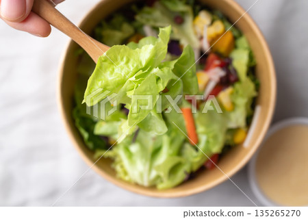 Healthy vegetable salad bowl with hand holding fork for eating, Top view, Close up Healthy vegetable salad bowl with hand holding fork for eating, Top view, Close up 135265270