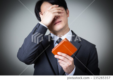 A middle-aged male businessman in a suit holding a wallet and worrying A middle-aged male businessman in a suit holding a wallet and worrying 135265357