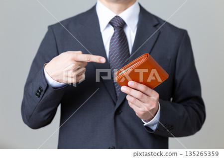 一位身穿西裝的中年男商人指著他的錢包 135265359