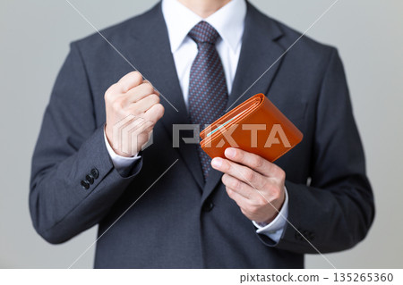 一位身穿西裝的中年男商人,手裡拿著錢包,揮舞著拳頭 一位身穿西裝的中年男商人,手裡拿著錢包,揮舞著拳頭 135265360