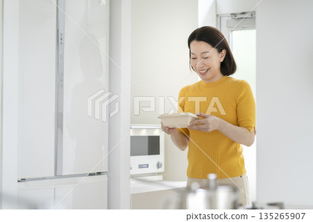A woman in her 50s holding a lunch box heated in a microwave 135265907