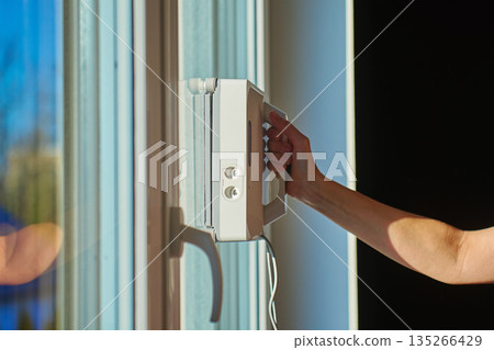 Woman starting robotic window cleaner on glass surface of window Woman starting robotic window cleaner on glass surface of window 135266429