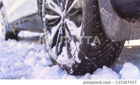 Car tires covered with snow and ice, harsh climatic conditions, operation of vehicles in winter, the condition of winter tires, features of driving in winter conditions, visualization of difficult  135267457