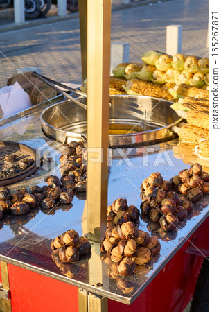 A street vendor sells roasted chestnuts and corn on the cob, a popular snack. 135267871