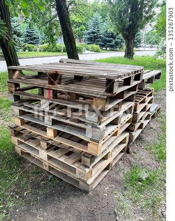 Stack of wooden pallets in a park setting, eco-friendly concept. 135267903