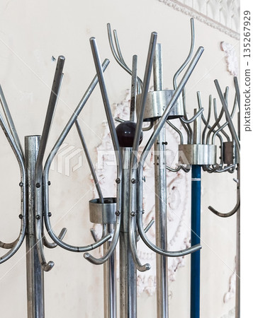 Vintage metal coat racks with hooks in an industrial interior setting. 135267929