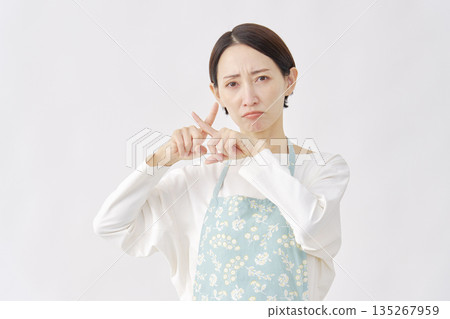 一位身穿圍裙的女子在白色背景上做出十字手勢。 135267959