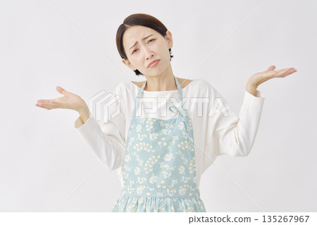 Woman wearing an apron making a gesture of giving up on a white background Woman wearing an apron making a gesture of giving up on a white background 135267967