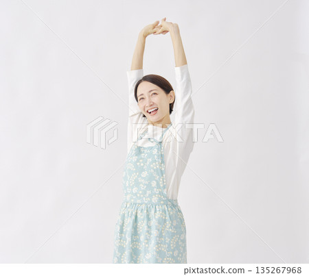 Woman wearing an apron stretching white background Woman wearing an apron stretching white background 135267968