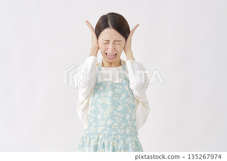 Woman wearing an apron covering her ears, white background Woman wearing an apron covering her ears, white background 135267974