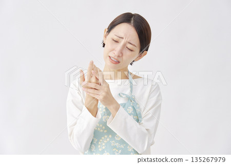 Woman wearing an apron with chapped and cracked hands, white background Woman wearing an apron with chapped and cracked hands, white background 135267979