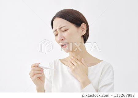 Woman measuring temperature with a thermometer on a white background Woman measuring temperature with a thermometer on a white background 135267992