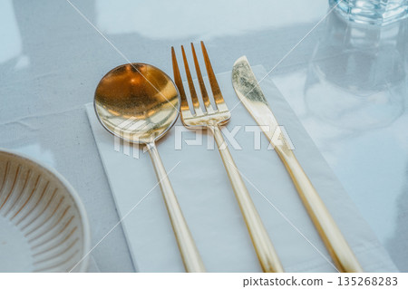 Modern Table Setting with Gold Cutlery and Ceramic Plate 135268283