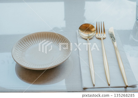 Modern Table Setting with Gold Cutlery and Ceramic Plate Modern Table Setting with Gold Cutlery and Ceramic Plate 135268285