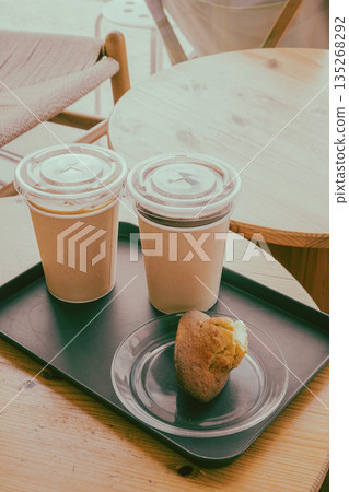 Two Takeout Coffees and a Muffin on a Wooden Table 135268292