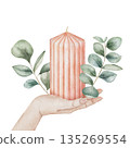 Watercolor illustration of a large ribbed candle decorated with eucalyptus branches held in a female hand, isolated on white background. Cozy and elegant element for holiday and winter compositions 135269554