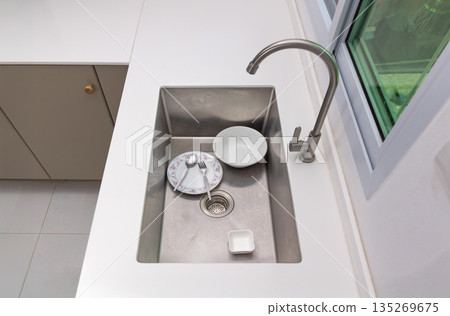 Clearing food scraps on dish to trash before clean in sink. Clearing food scraps on dish to trash before clean in sink. 135269675