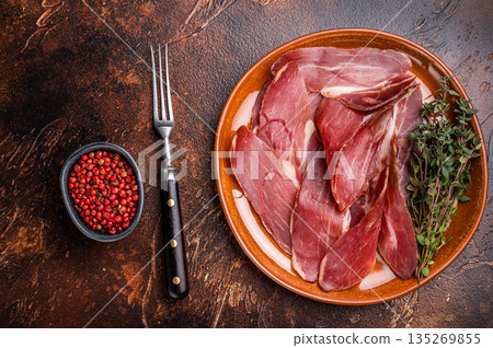 Balkan Prsut prshut, sliced cured pork meat ham on plate. brown background. top view 135269855