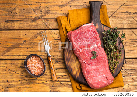 Fresh raw bison meat displayed on a wooden board, showcasing its rich red color and tenderness, ideal for gourmet cooking adventures. wooden background. top view 135269856