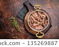 Close-up of succulent pulled brisket piled high on a rustic wooden board, garnished with fresh herbs, delicious meal. brown background. top view 135269887