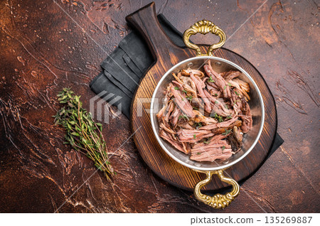 Close-up of succulent pulled brisket piled high on a rustic wooden board, garnished with fresh herbs, delicious meal. brown background. top view Close-up of succulent pulled brisket piled high on a rustic wooden board, garnished with fresh herbs, delicious meal. brown background. top view 135269887