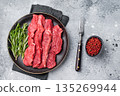 Raw bison meat presented with fresh herbs and spices, inspiring bold flavors and unique recipes for adventurous food lovers. grey background. top view 135269944