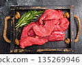 Vibrant raw bison meat pieces on a butcher block, illustrating the allure of this lean protein source for health-conscious culinary enthusiasts. black background. top view 135269946