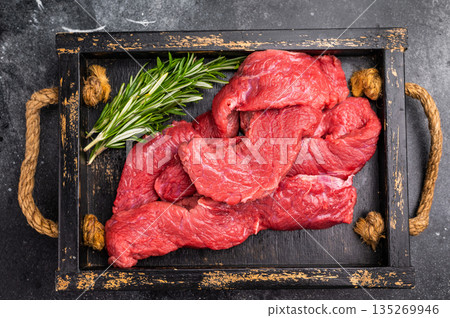 Vibrant raw bison meat pieces on a butcher block, illustrating the allure of this lean protein source for health-conscious culinary enthusiasts. black background. top view 135269946