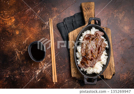Exquisite Japanese BBQ, highlighting beautifully charred meats and rice. Perfectly seasoned, this dish promises a rich and savory flavor in every bite. brown background. top view Exquisite Japanese BBQ, highlighting beautifully charred meats and rice. Perfectly seasoned, this dish promises a rich and savory flavor in every bite. brown background. top view 135269947