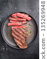 Grilled New York Striploin steak, perfectly seared with beautiful grill marks, showcasing its juicy tenderness and rich flavor. black background. top view 135269948