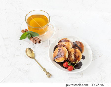 Curd fritters on the porcelain plate with a cup of tea. Curd fritters on the porcelain plate with a cup of tea. 135270299