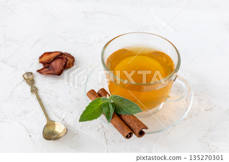 Glass cup of green tea with cinnamon and leaves of mint on a saucer. 135270301