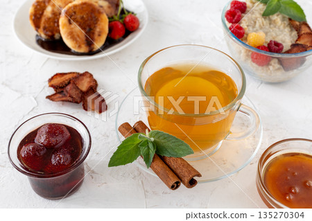 Glass cup of green tea with cinnamon and leaves of mint on a saucer. 135270304