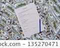 An empty contract lies on a pile of money, ready for signing and filling out 135270471