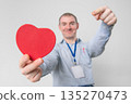 Smiling cardiologist doctor holding a healthy heart in his hands 135270473