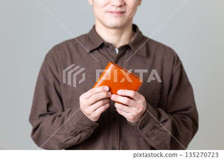 A middle-aged male businessman in casual clothes holding a wallet A middle-aged male businessman in casual clothes holding a wallet 135270723