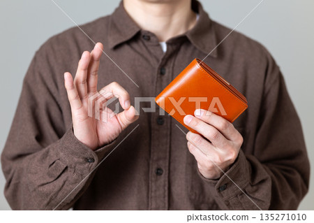 A middle-aged male businessman in casual clothes holding a wallet and making a circle sign A middle-aged male businessman in casual clothes holding a wallet and making a circle sign 135271010