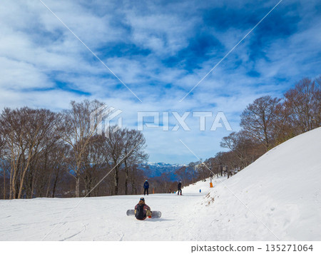 A view of the snowy mountains and people preparing to ski at the top of a ski resort under a wide winter sky (Tanbara, Numata City, Gunma Prefecture) A view of the snowy mountains and people preparing to ski at the top of a ski resort under a wide winter sky (Tanbara, Numata City, Gunma Prefecture) 135271064