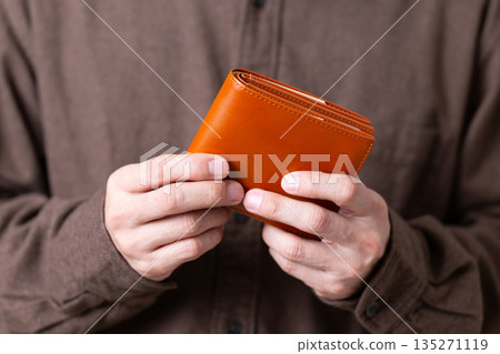 一位身著休閒裝的中年男性商務人士，手裡拿著錢包 135271119